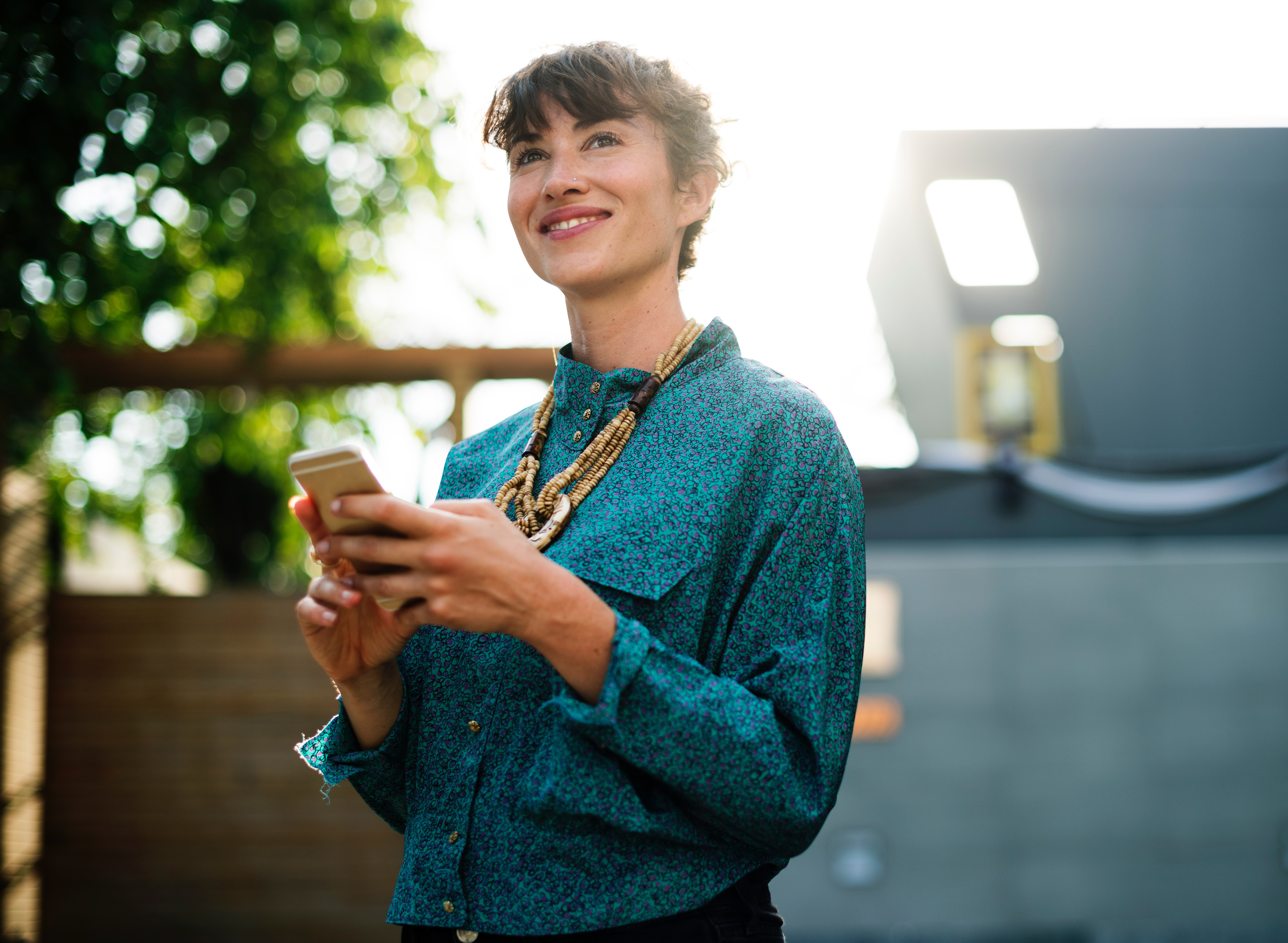 White woman looking up while holding her phone | Purple Horizons